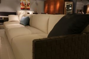 A beige couch with dark accent pillows in a dimly lit living room.