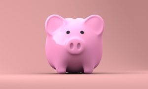 Front view of a pink pig-shaped savings bank against a peach-colored background.