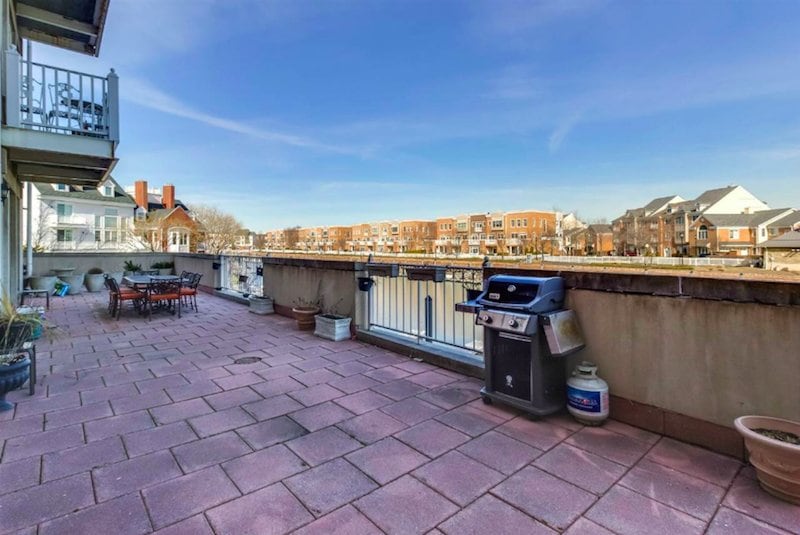 A paved patio overlooking a canal and a row of Port Liberte townhomes.